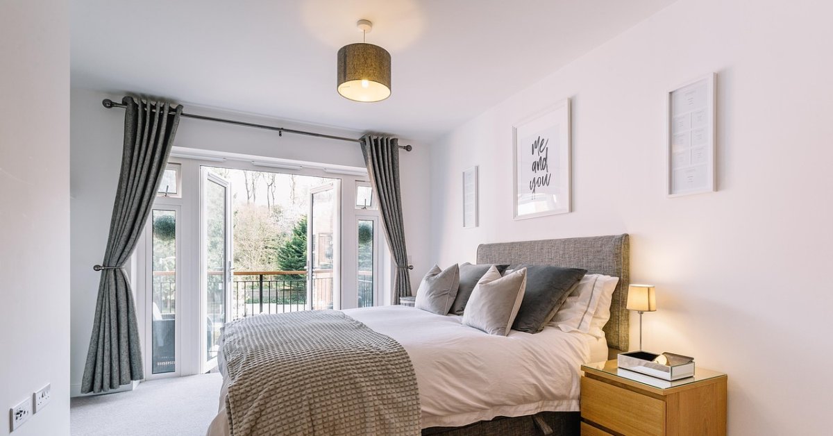 Lichte slaapkamer met een wit raamkozijn, gordijnen en een tweepersoonsbed